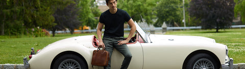 model using brown leather briefcase in front of white car