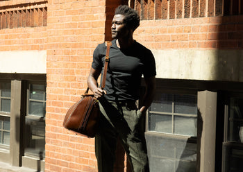 man carrying leather duffle bag by shoulder strap