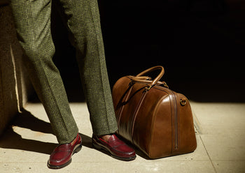 brown men's leather travel bag next to shoes