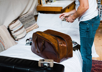 man packing leather duffle bag